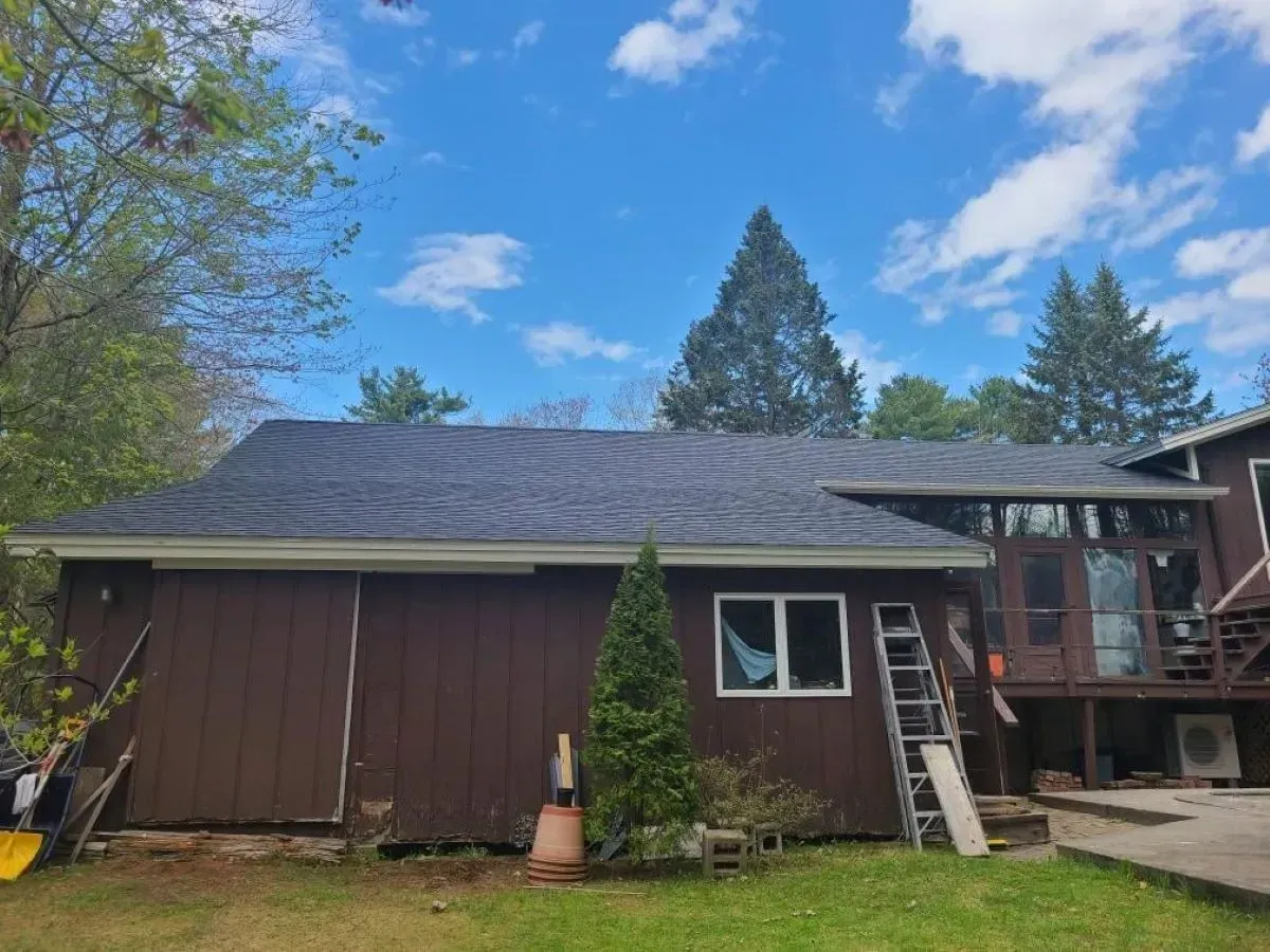 A brown house with a ladder in front of it and a blue sky in the background.