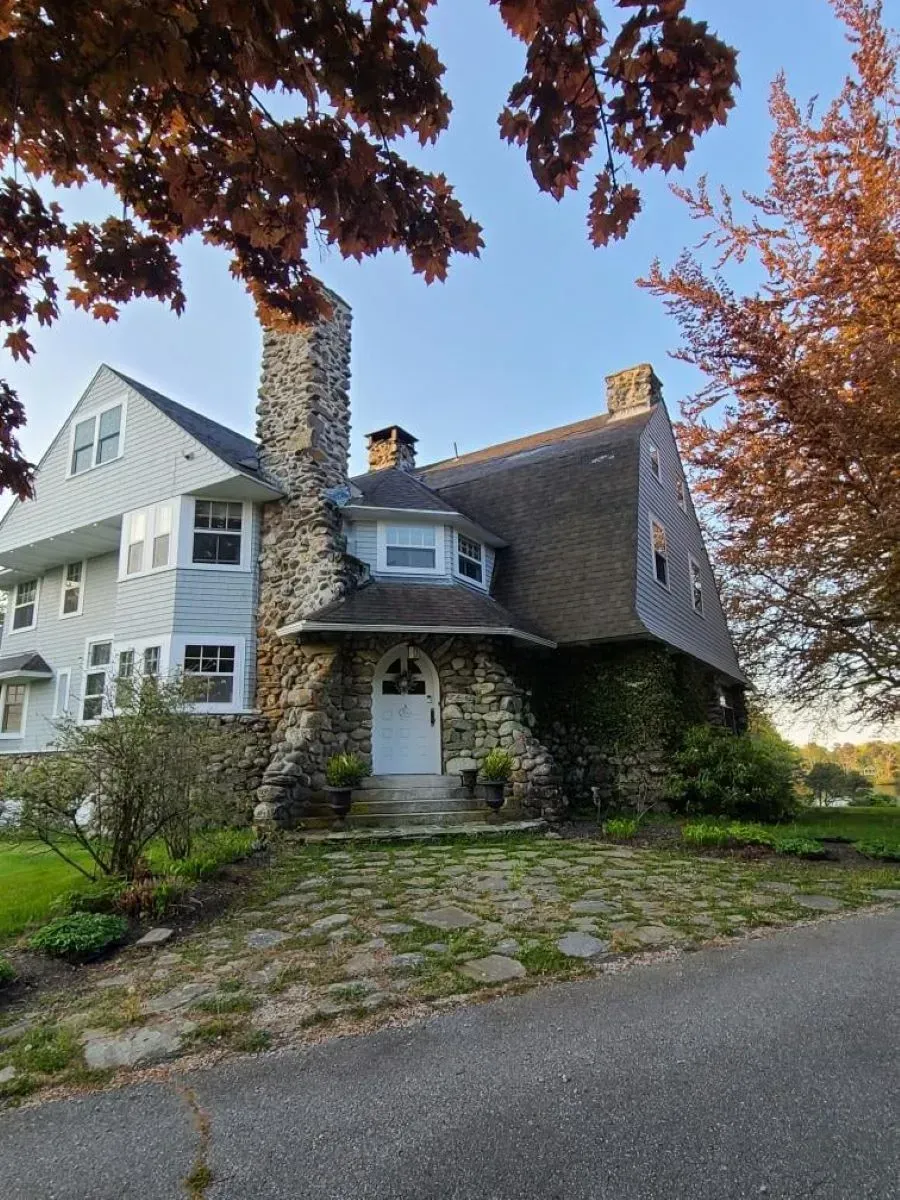 A large house with a stone chimney and a stone driveway