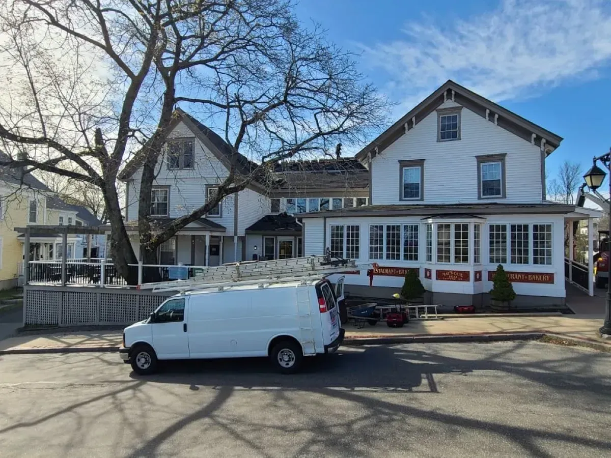A white van is parked in front of a large white house.