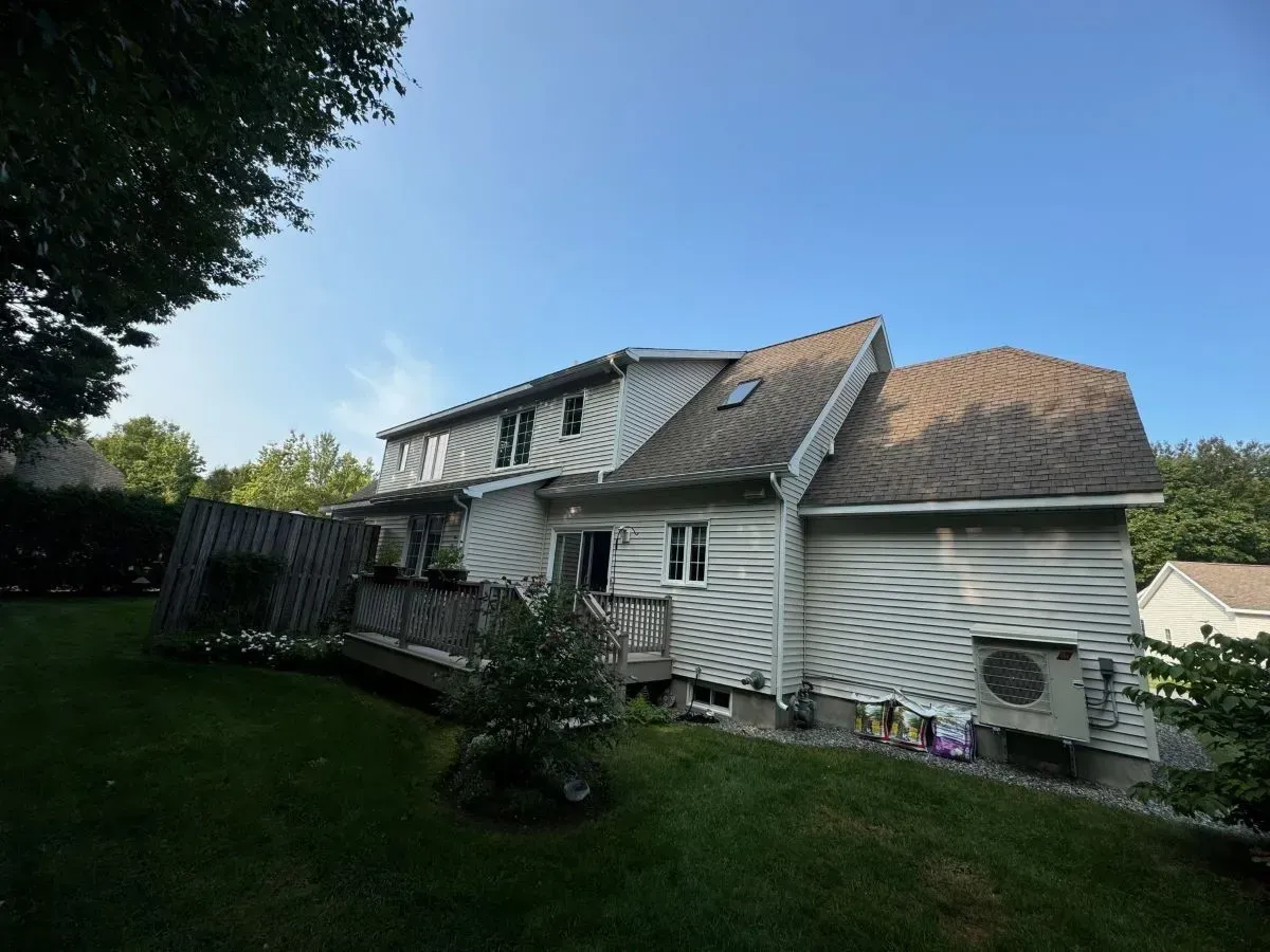 A white house with a brown roof and a deck