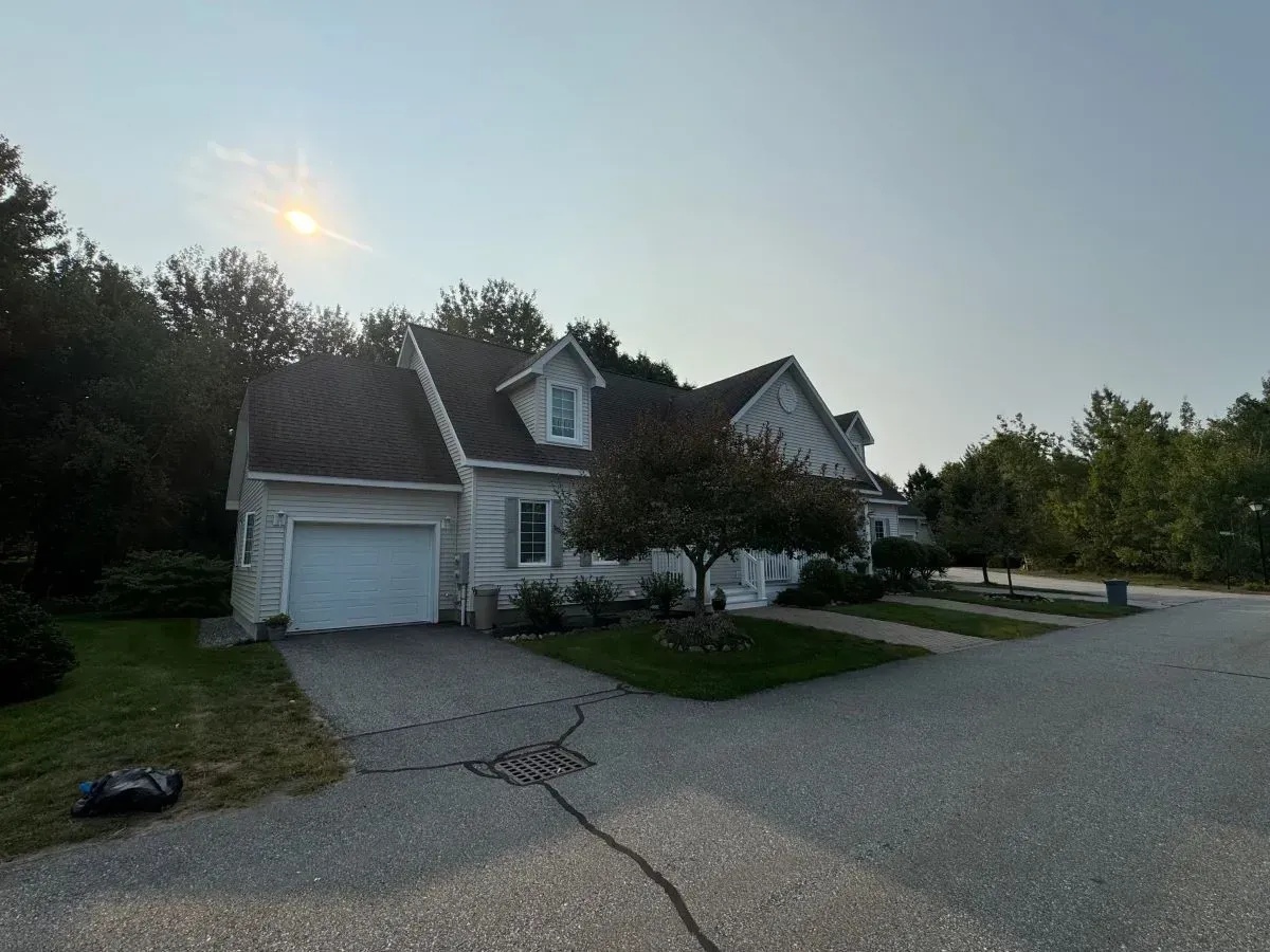 A white house with a black roof and a garage