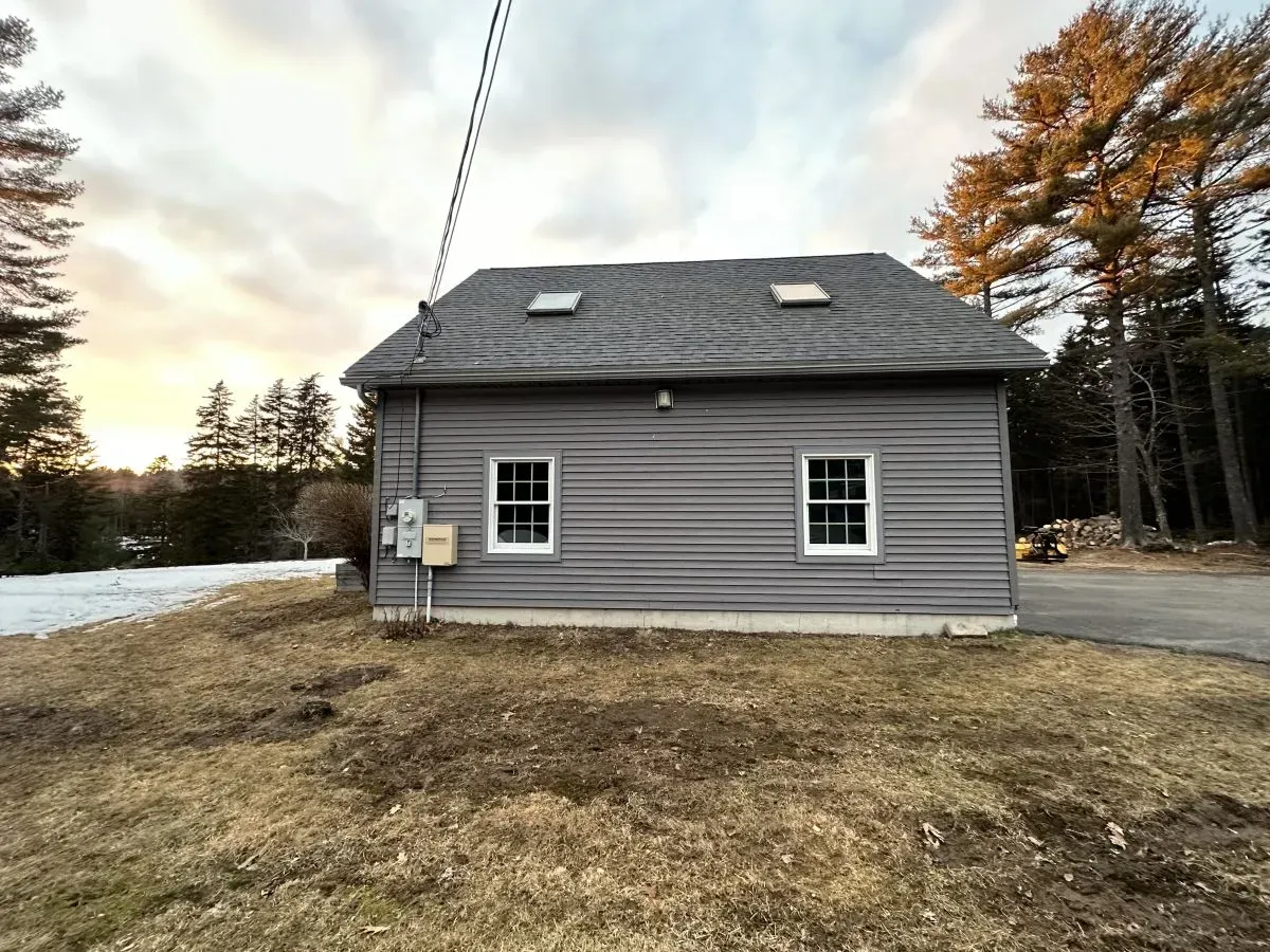 A small house with a roof that has a skylight is sitting in the middle of a field.