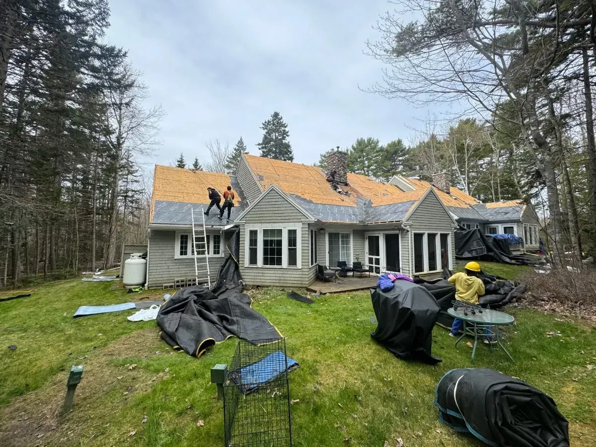 A group of people are working on the roof of a house.