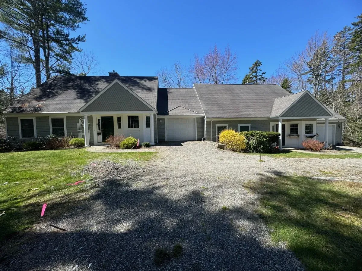 A large house with a gravel driveway in front of it.