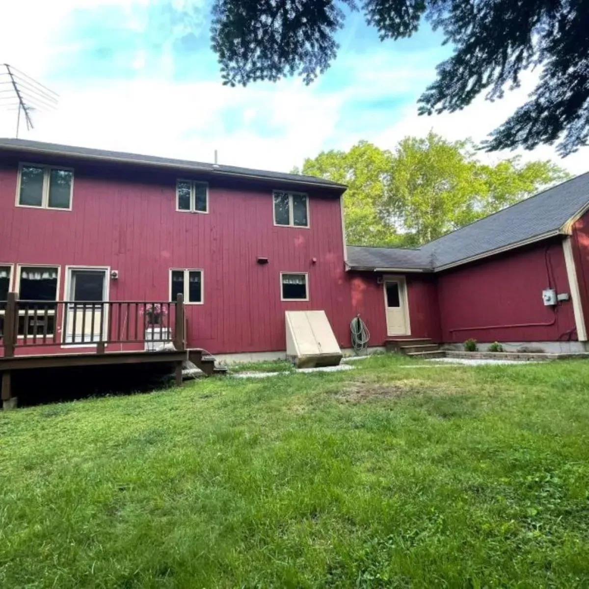 A red house with a deck in the backyard