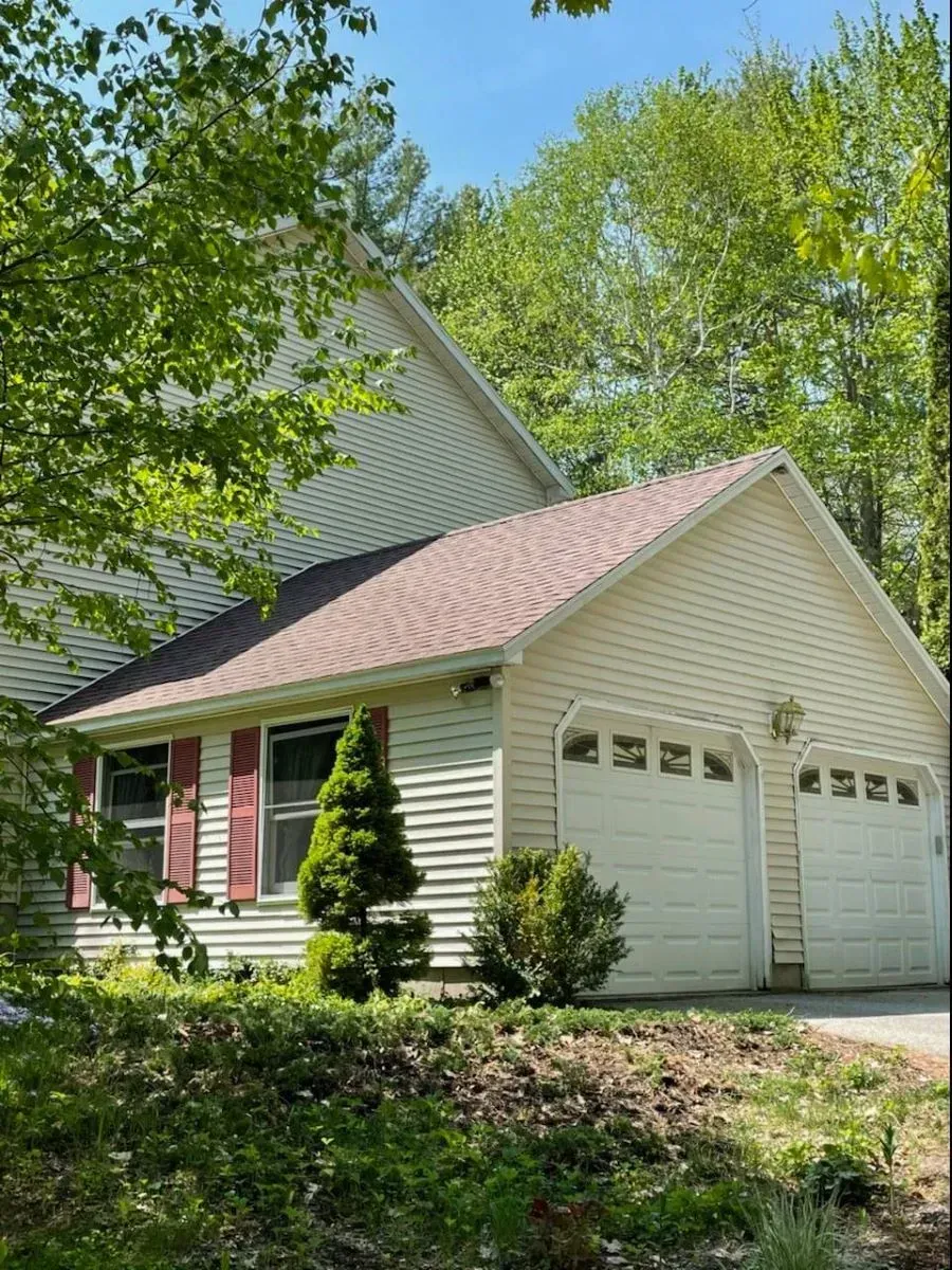 A white house with a pink roof and red shutters