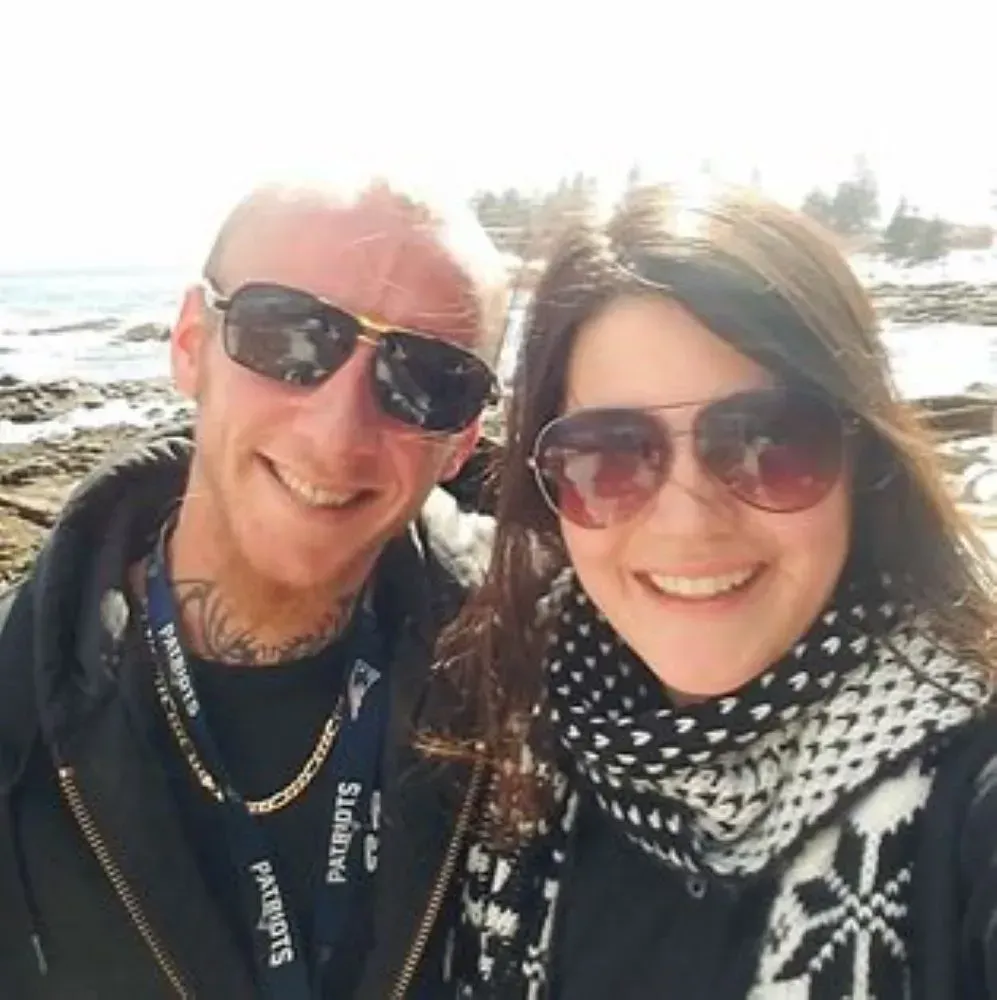 A man and a woman wearing sunglasses and a patriots lanyard