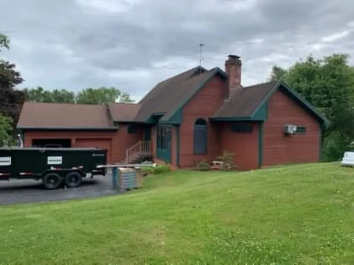 A brick house with a black dumpster in front of it