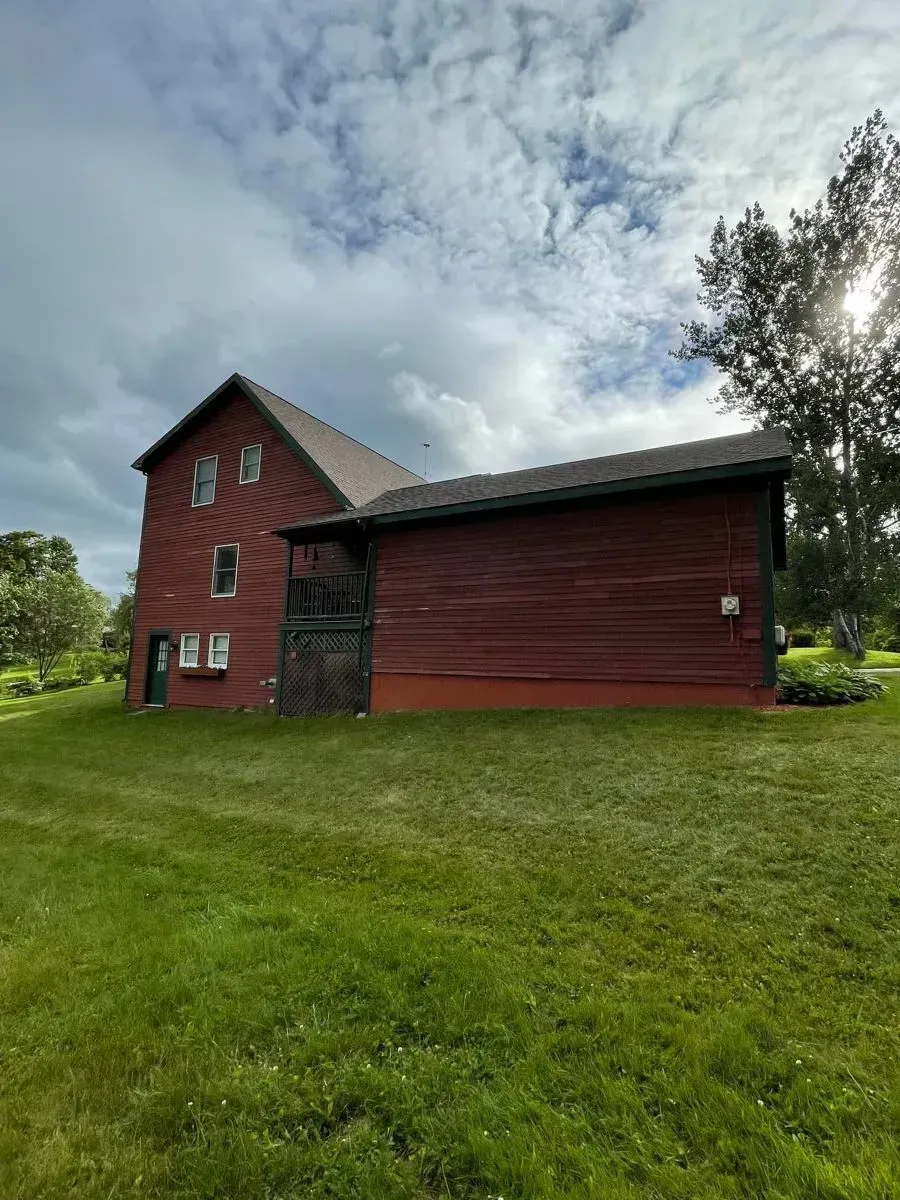 A red barn is sitting in the middle of a lush green field.