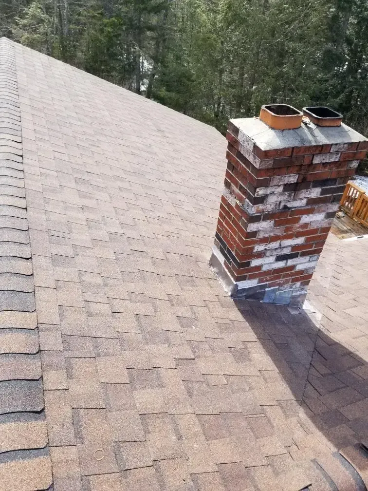 A brick chimney is sitting on top of a roof.