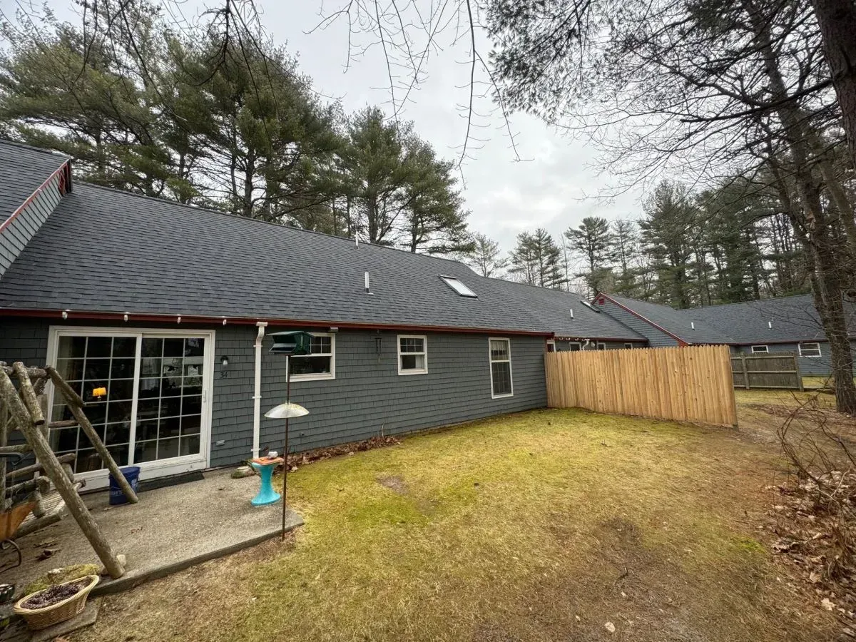 The backyard of a house with a sliding glass door and a wooden fence.