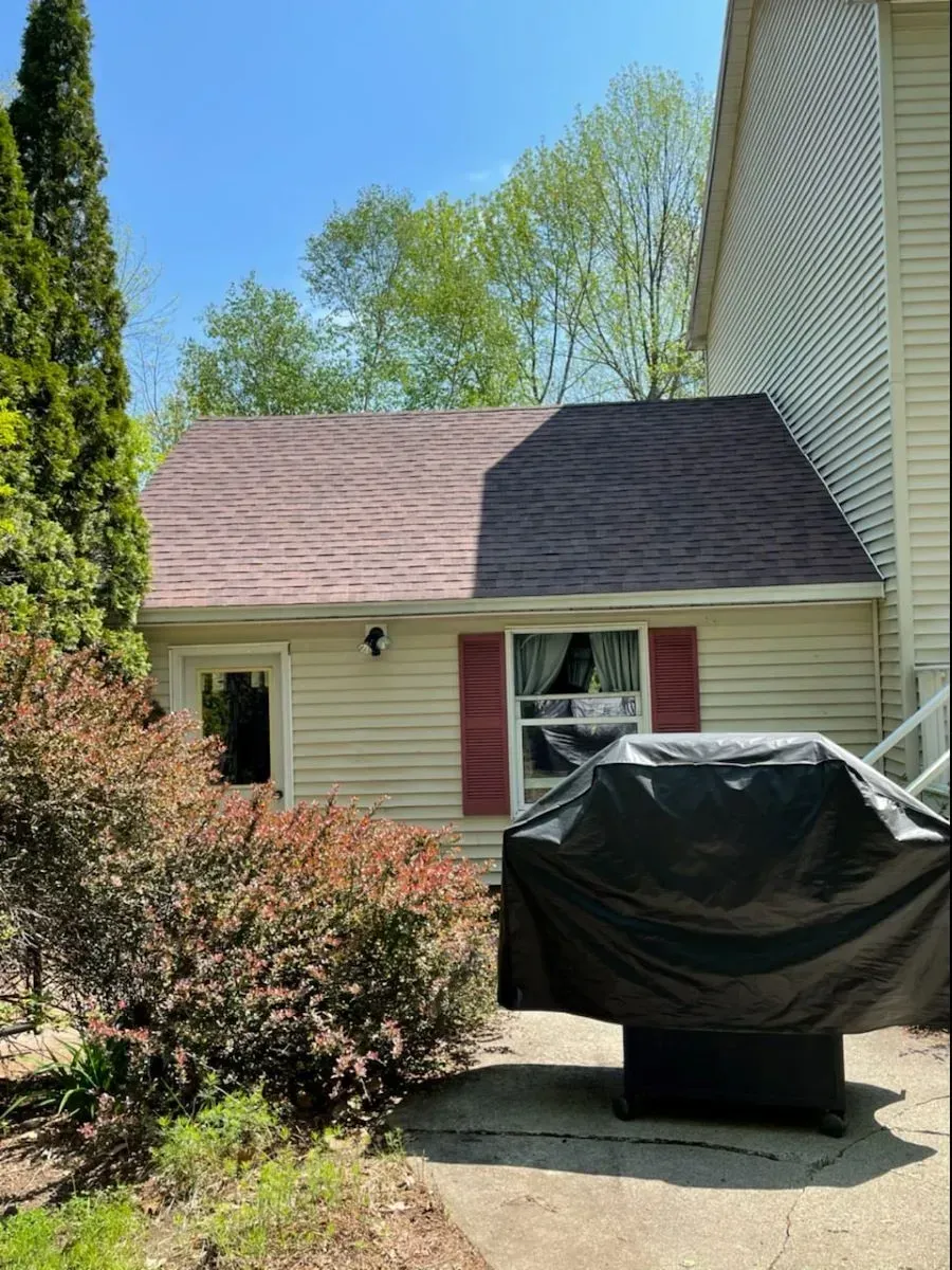 A grill is covered in a black tarp in front of a house.