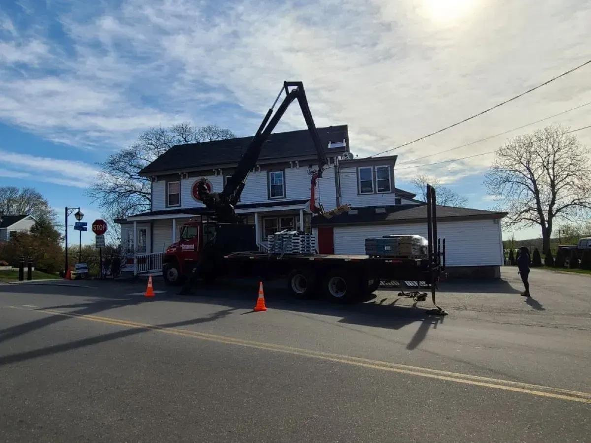 A truck with a crane on top of it is parked in front of a house.