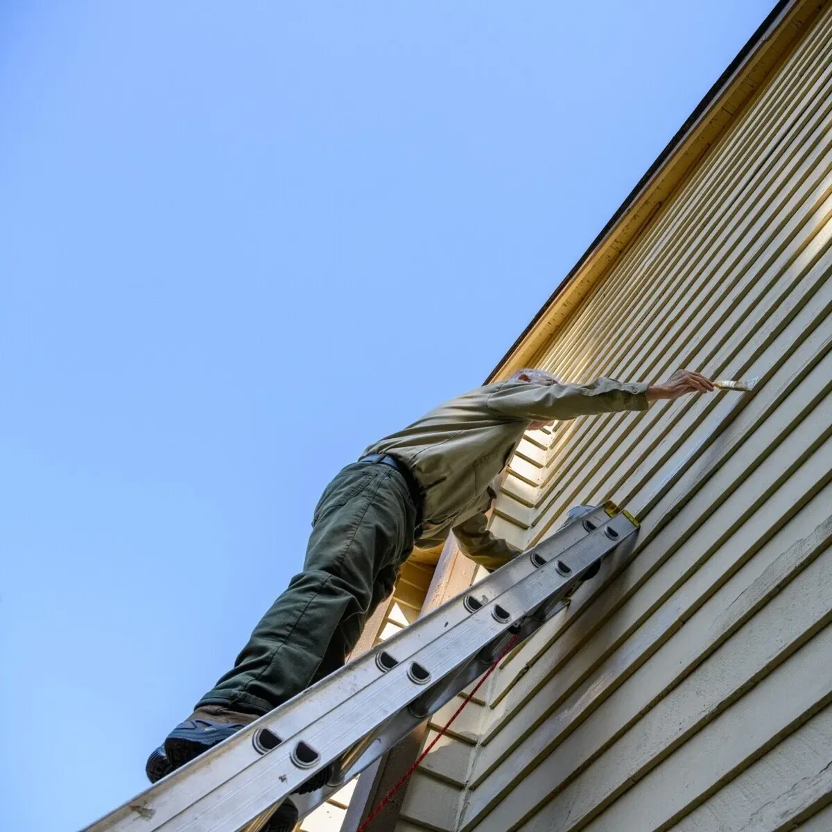 A man is climbing up a ladder on the side of a building