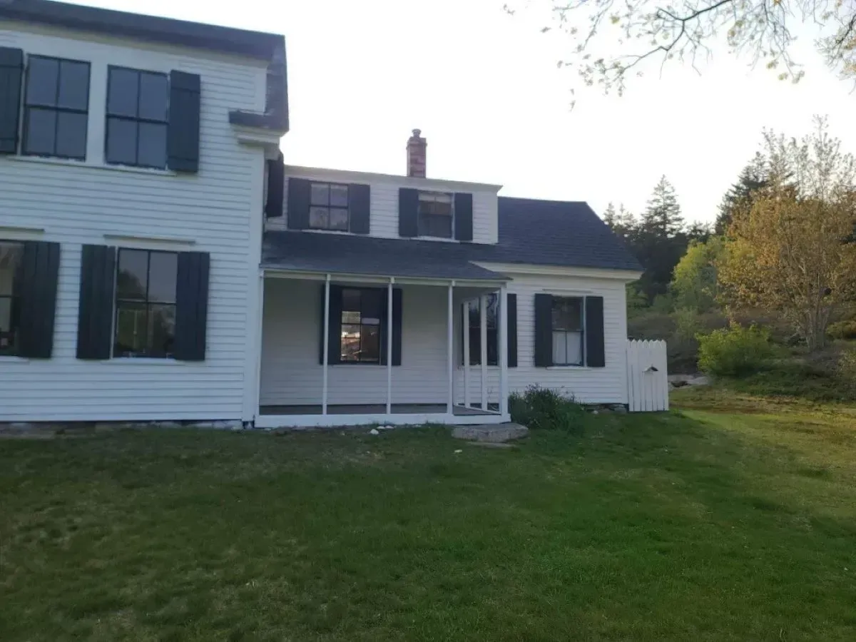 A white house with black shutters and a porch