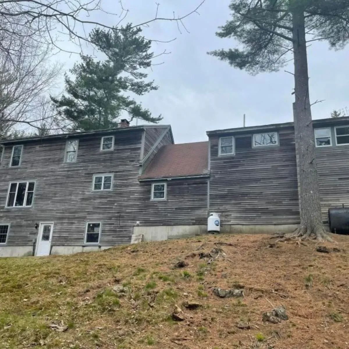 A large wooden house sits on top of a grassy hill