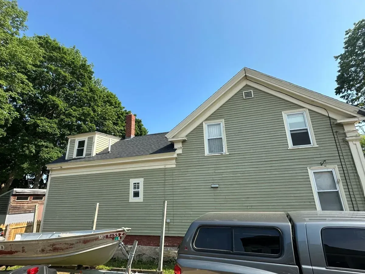 A house with a boat in front of it and a truck parked in front of it.