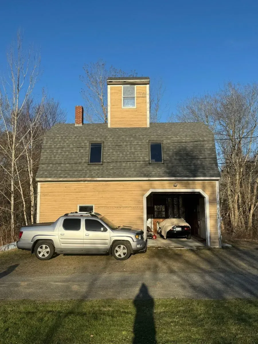 A truck is parked in front of a house with a garage.