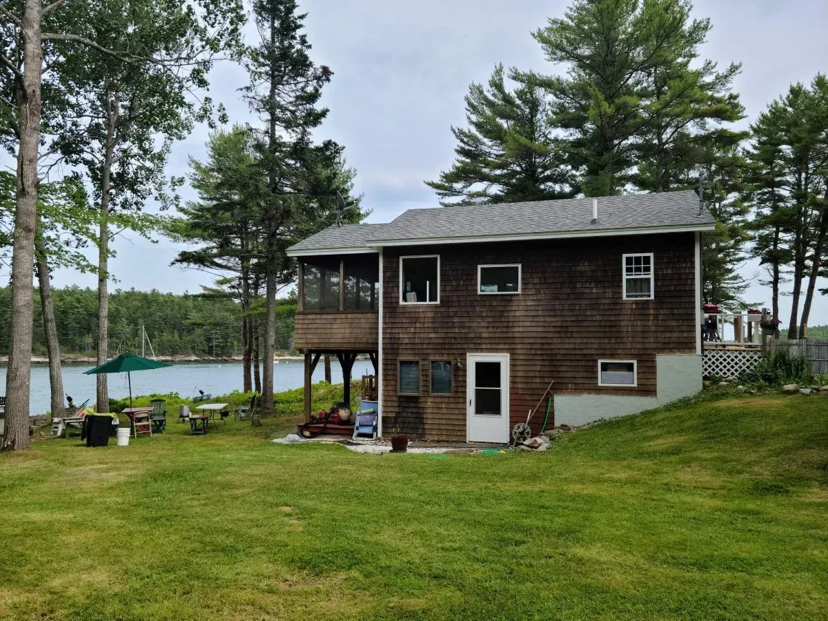 A house with a large lawn in front of it and a lake in the background