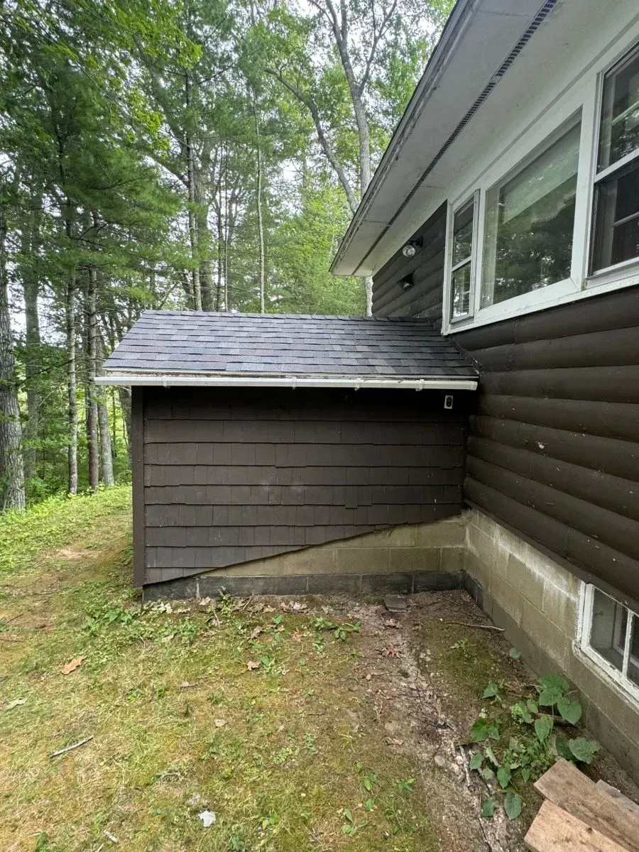 A brown house with a shed on the side of it.