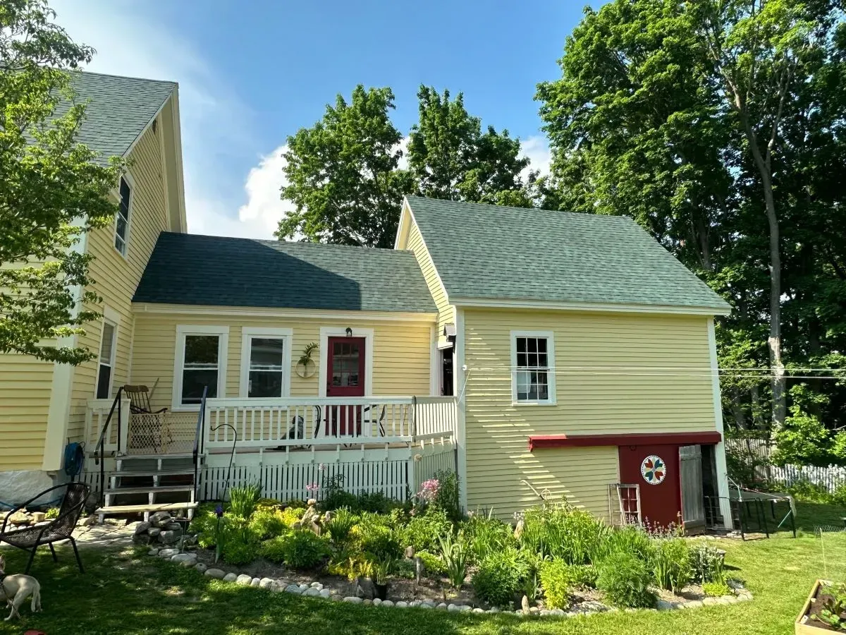 A yellow house with a green roof and a red door