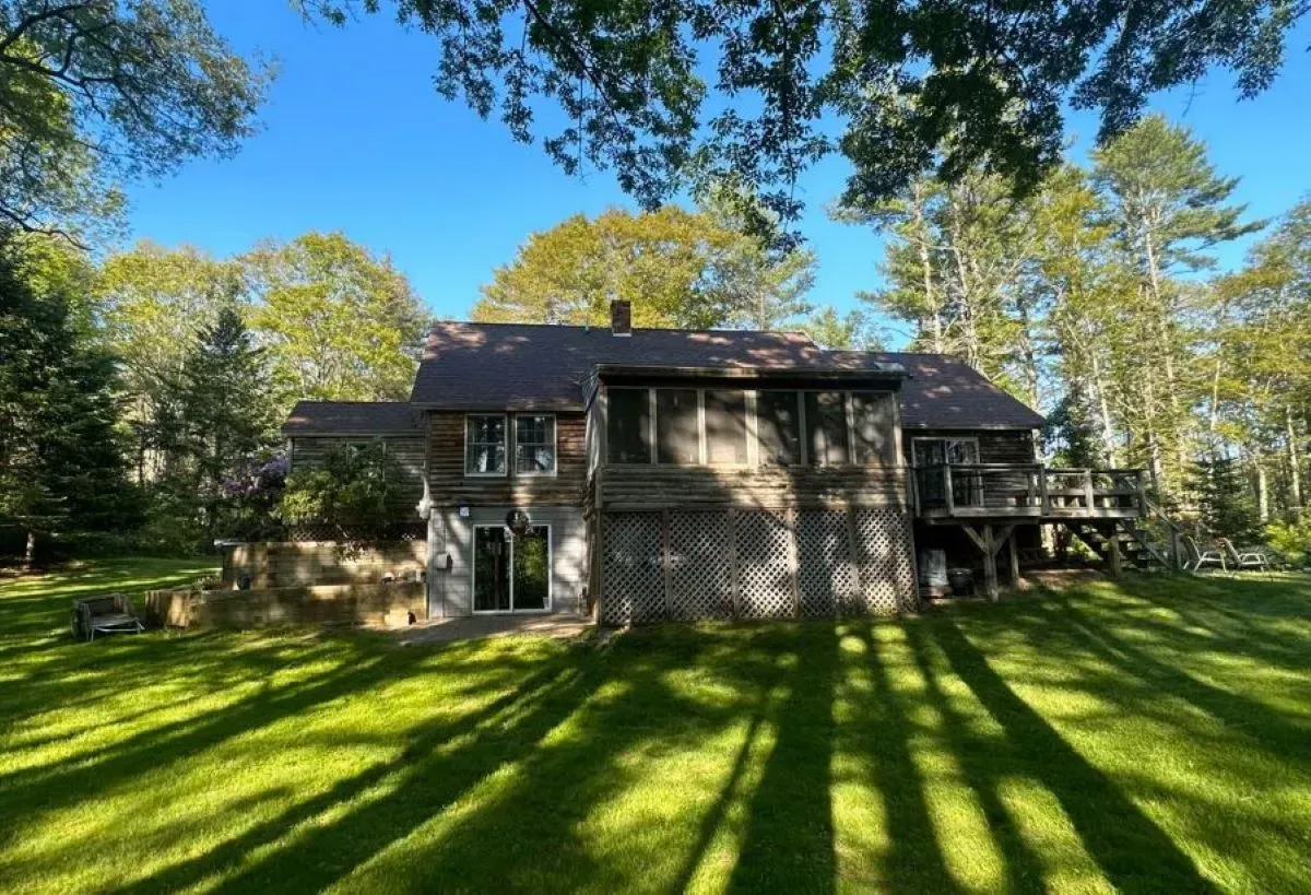 A large house is sitting on top of a lush green lawn surrounded by trees.