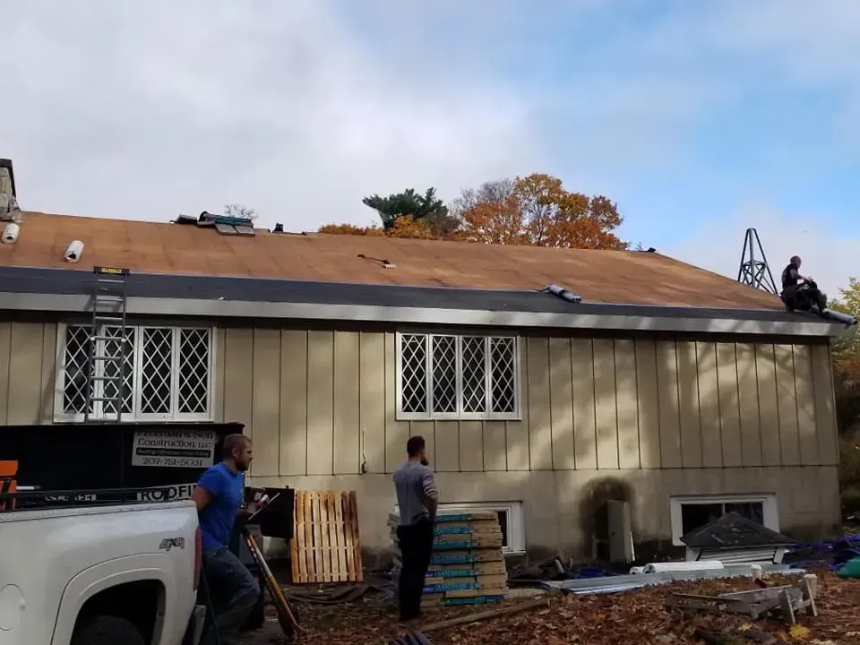 Two men are working on the roof of a house.