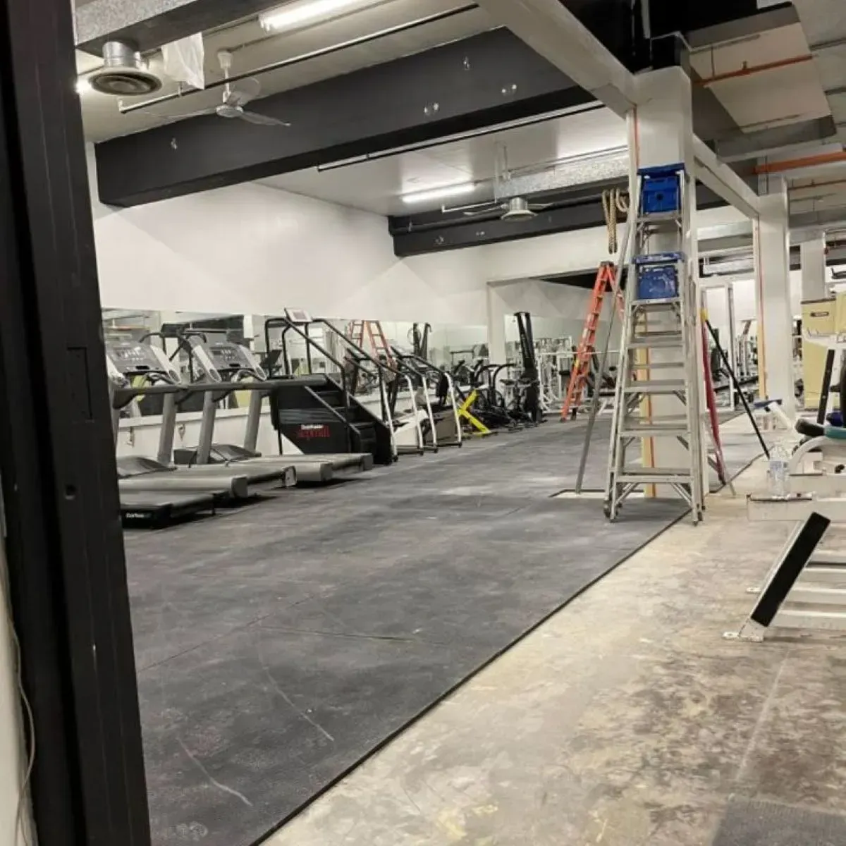 A gym with treadmills and stairs and a ladder