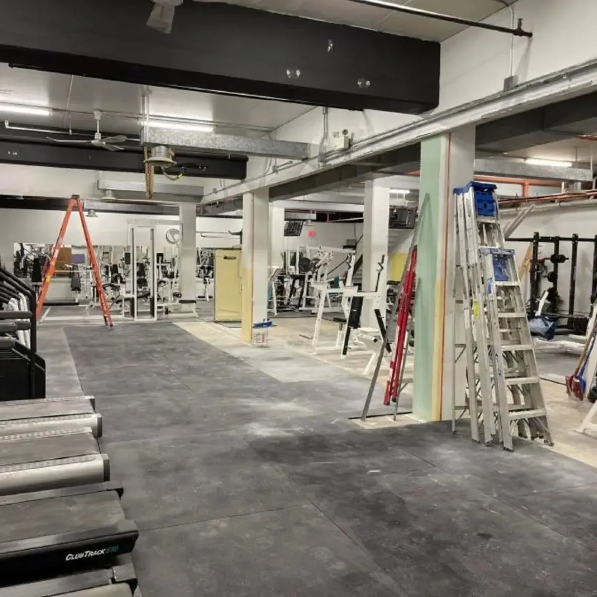 An empty gym with a treadmill and a ladder