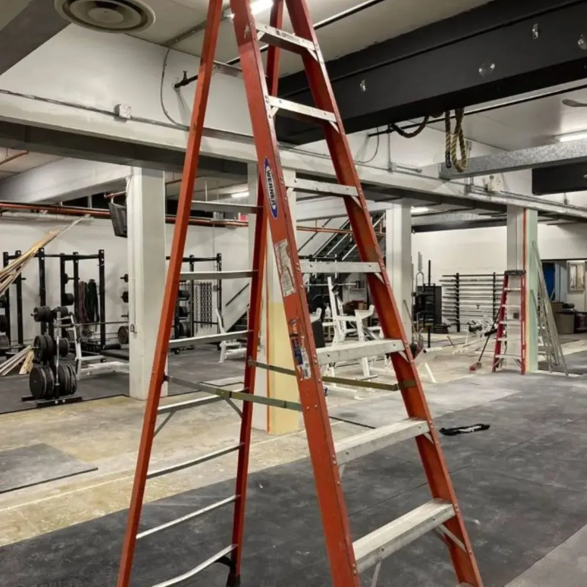 A red ladder is sitting in a gym