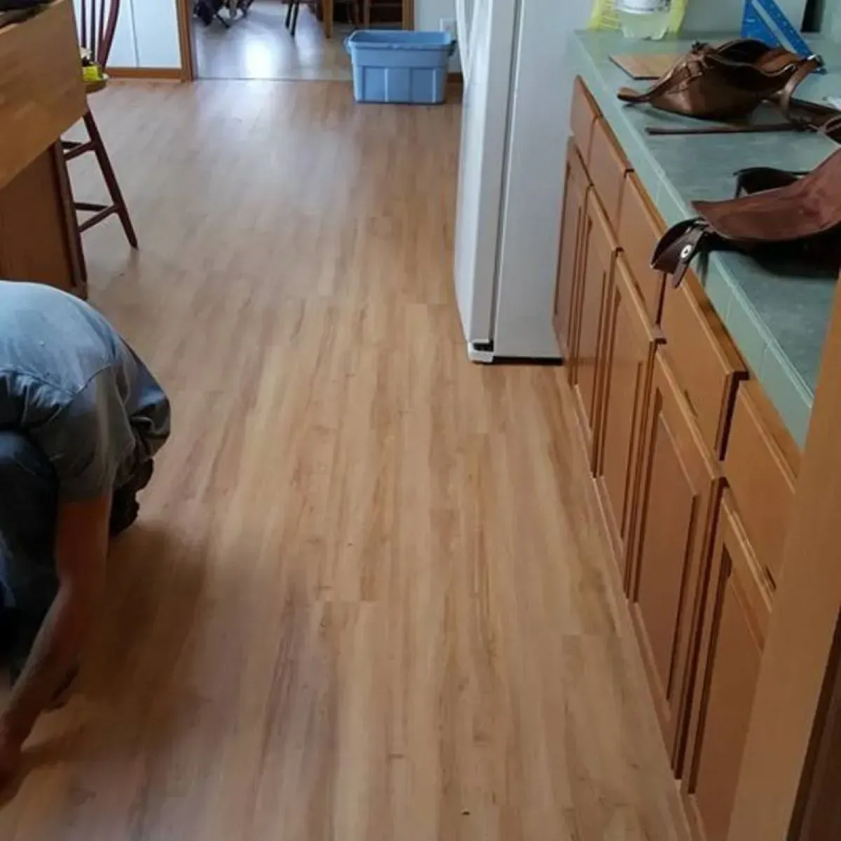 A man is kneeling on the floor in a kitchen