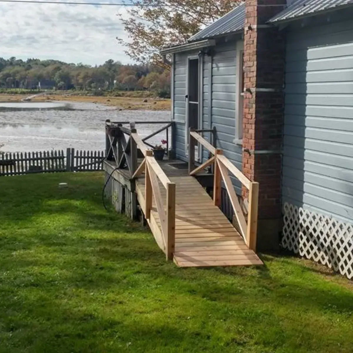 A wooden ramp leading to a house next to a body of water.