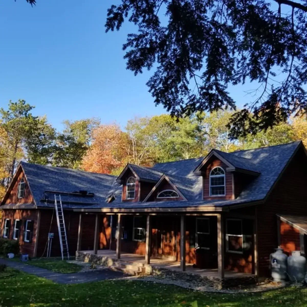 A large house with a porch and a ladder in front of it