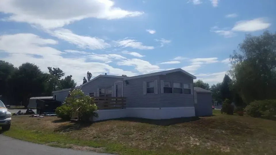 A mobile home is sitting on top of a grassy hill next to a road.