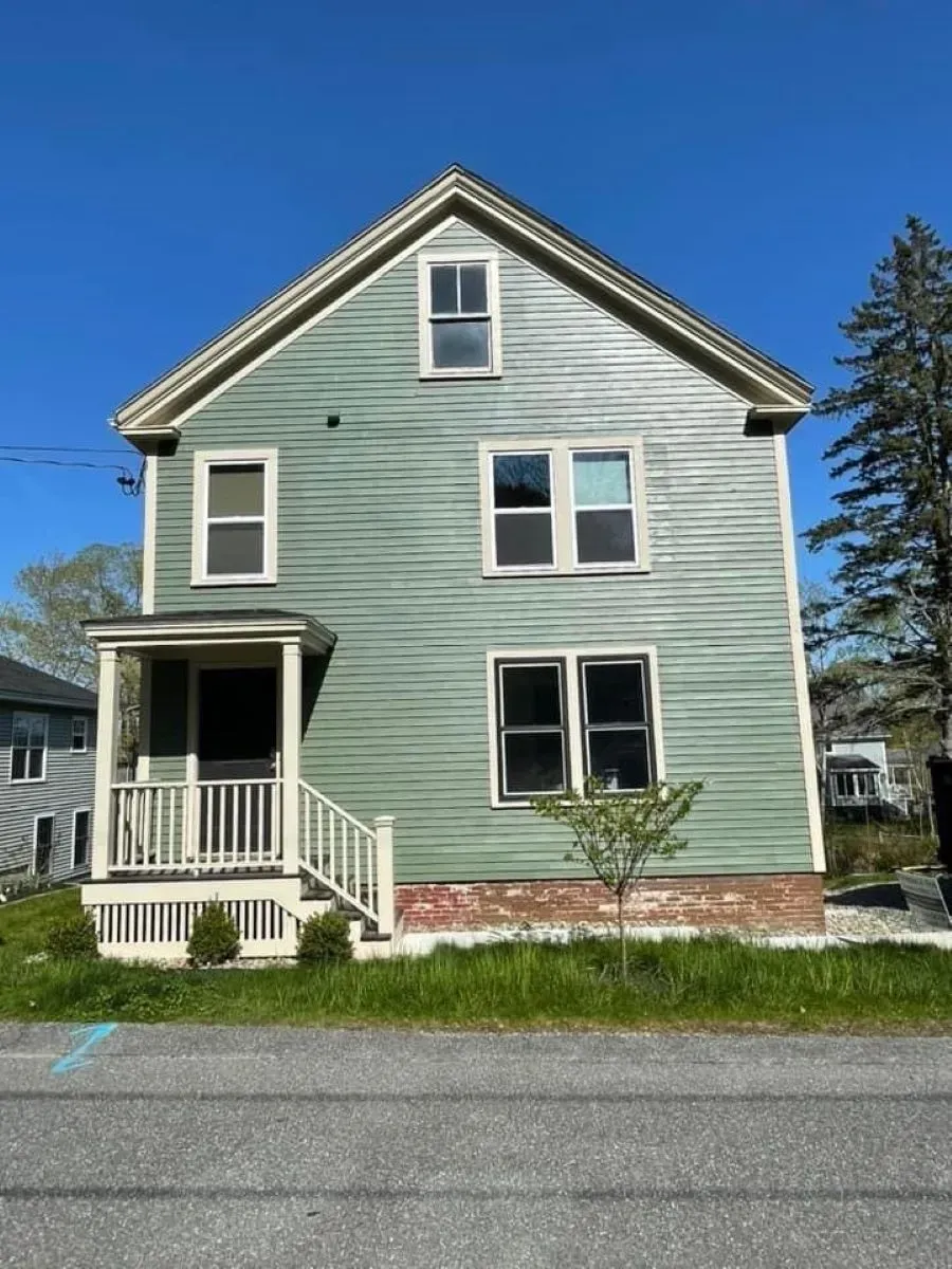 A green house with a white porch and stairs