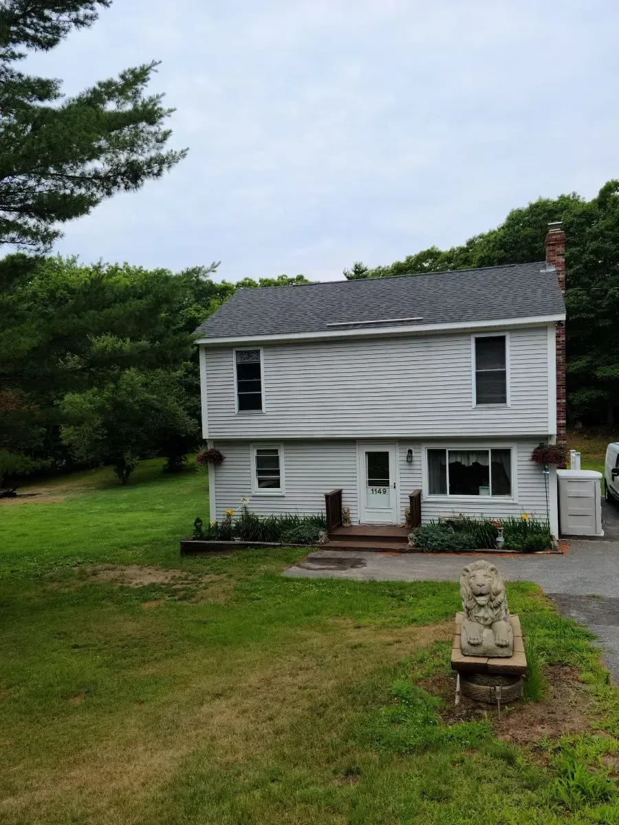 A white house sits in the middle of a lush green field