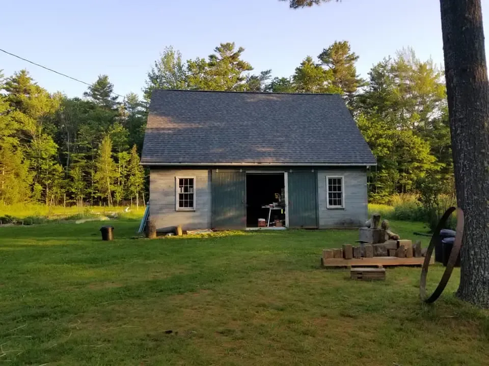 A small house is sitting in the middle of a grassy field.