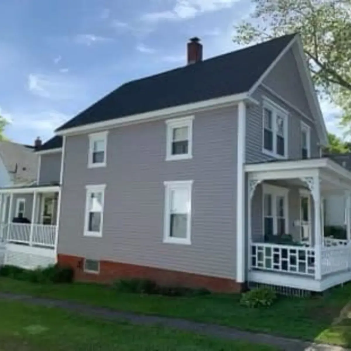 A gray house with a black roof and a porch