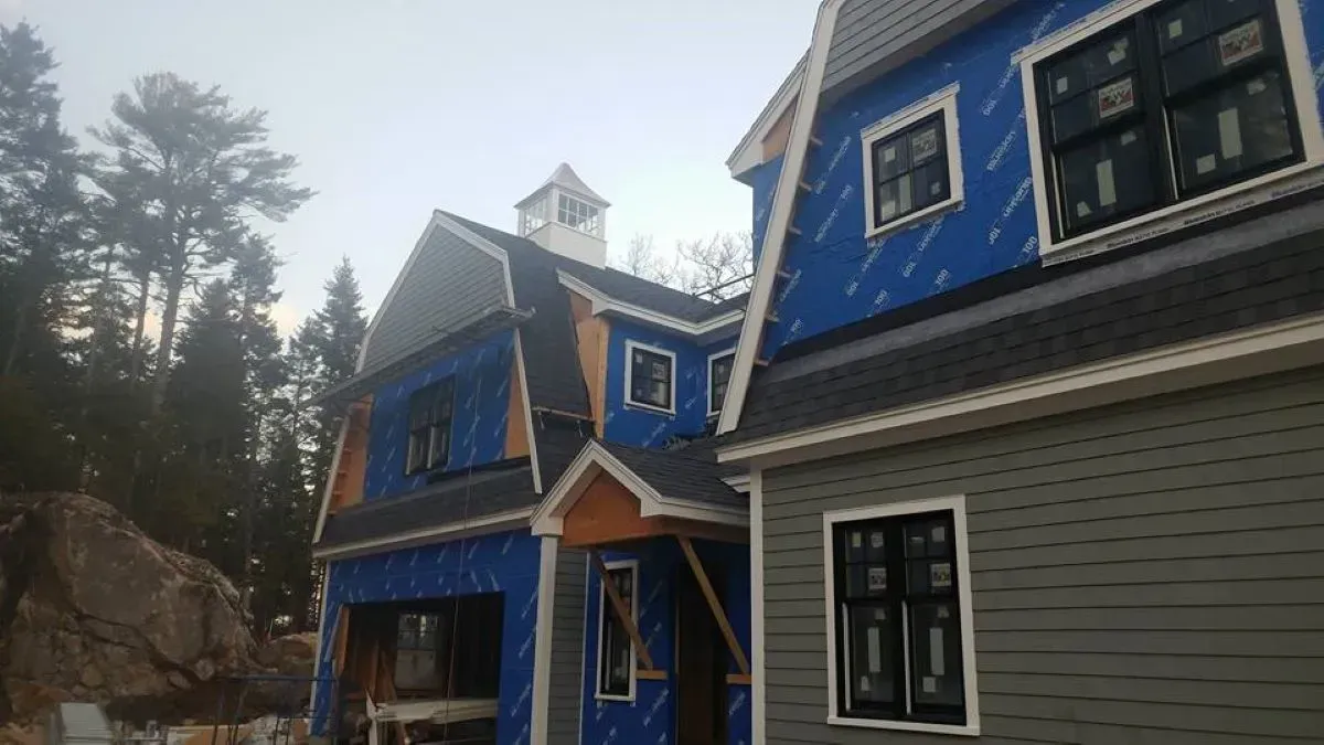 A blue and gray house is being built in the woods.