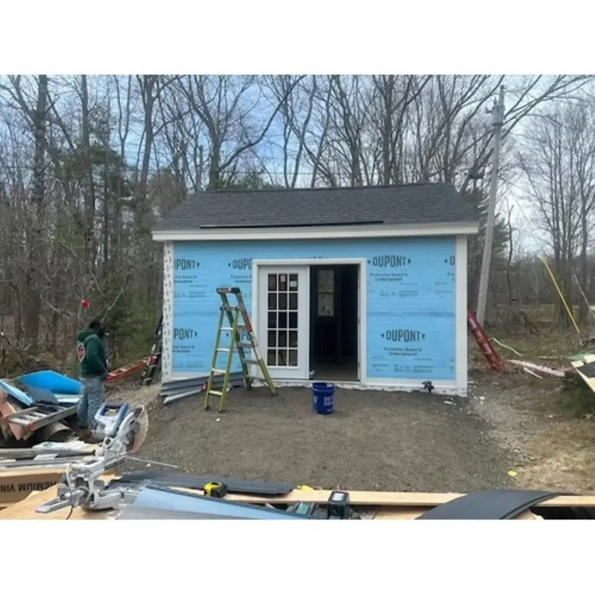 A man is standing in front of a shed that is being built.