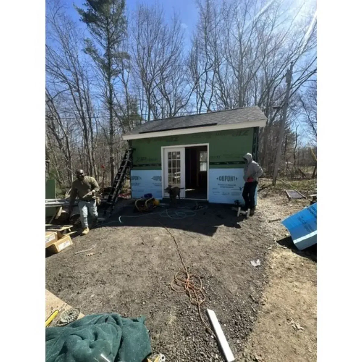 A man is standing in front of a shed that is being built