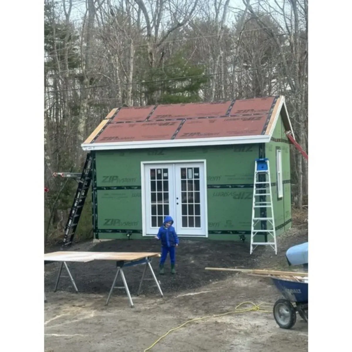 A boy is standing in front of a green building under construction