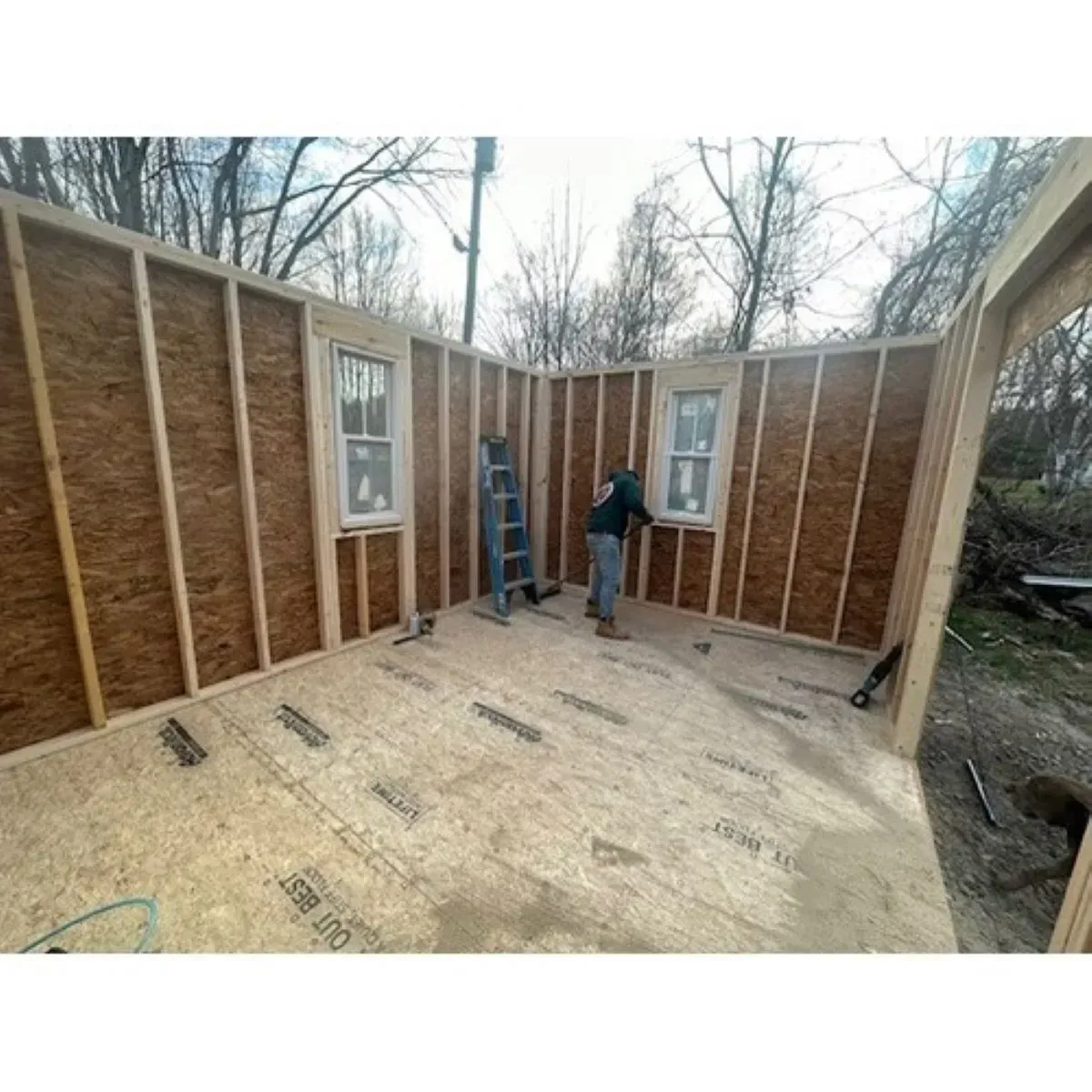 A man is standing in a room that is being built.