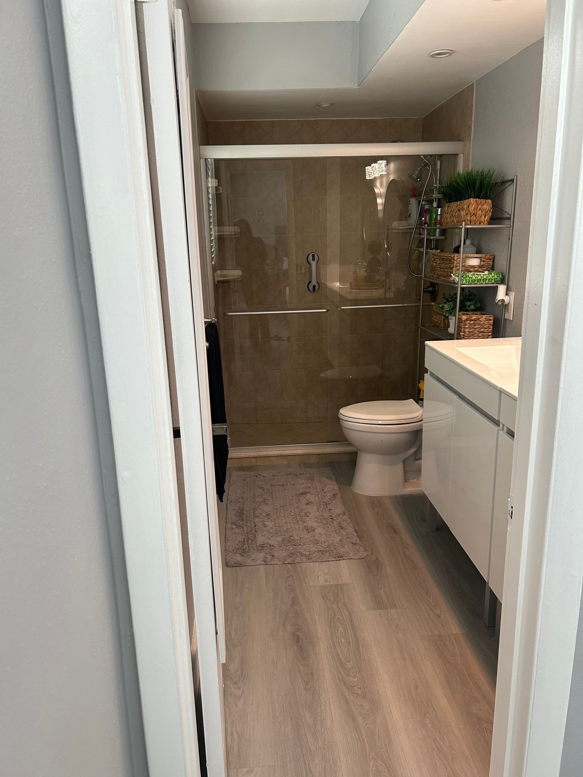 A bathroom with a toilet , sink and shower.