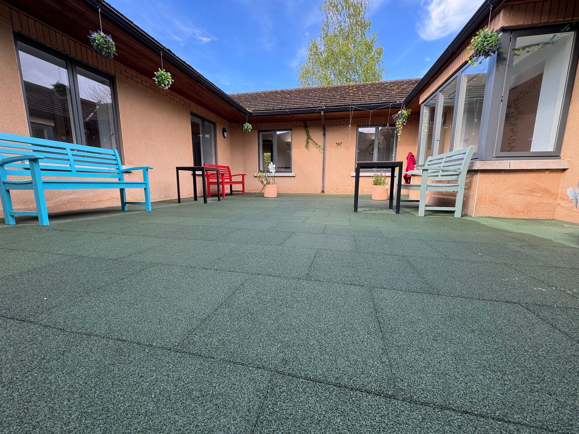 Care home outdoor courtyard with colourful benches and rubber safety flooring