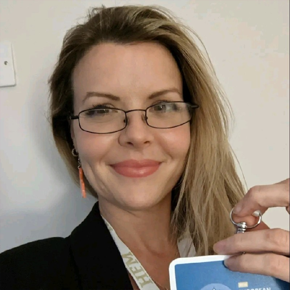 A woman wearing glasses and a lanyard with the letter h on it