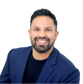 A man with a beard is wearing a blue suit and smiling