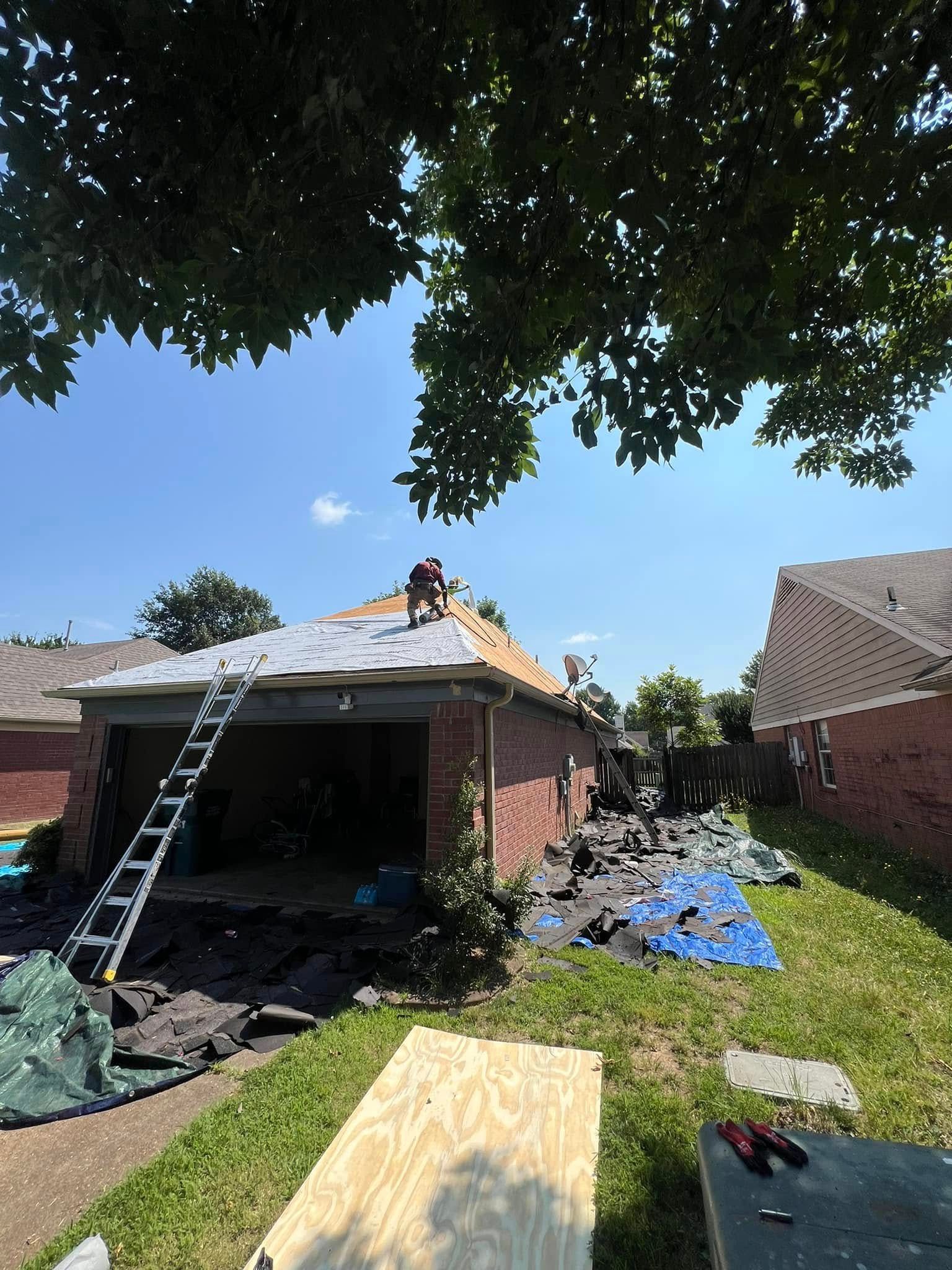 Damaged house roof under repair, with ladder, workers, and scattered debris in the yard.