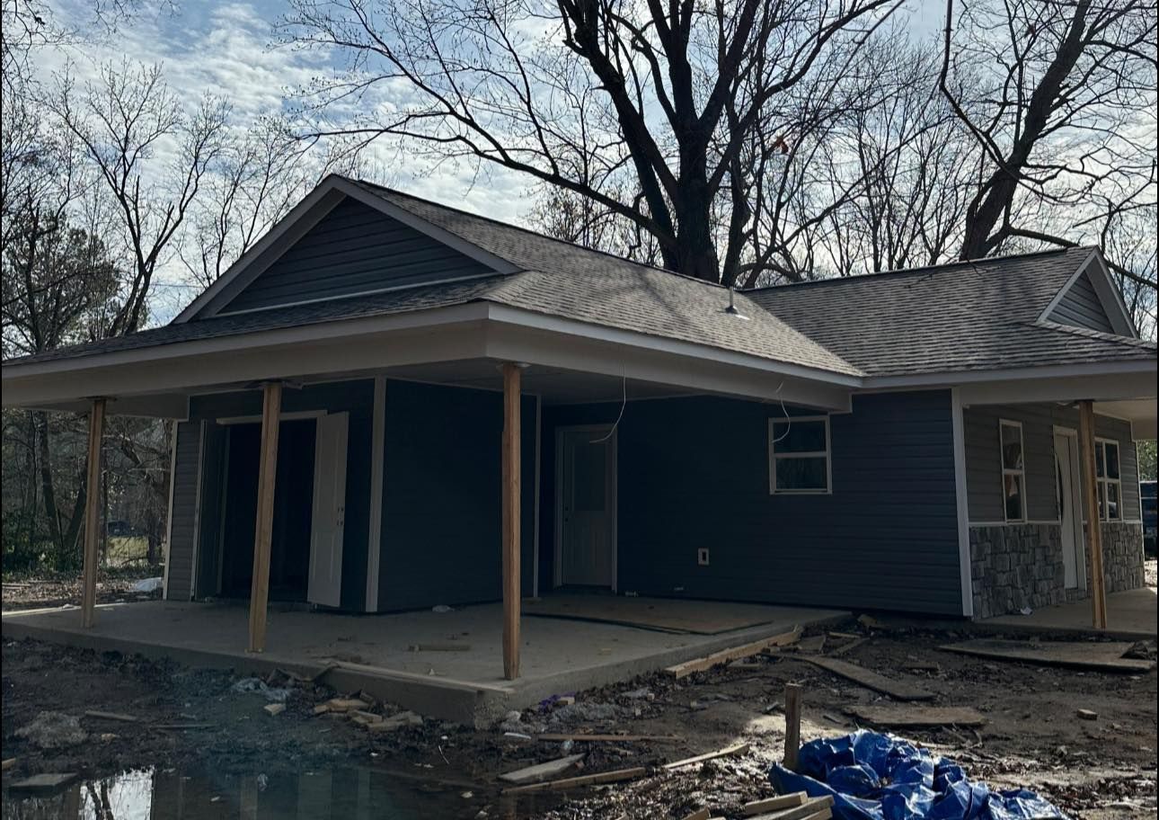 Damaged blue house with a covered porch and debris in the yard after a fire or storm
