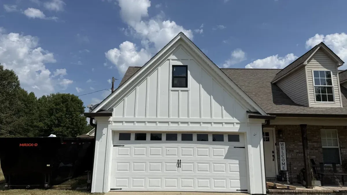 White two-story house exterior with a double garage under a partly cloudy sky